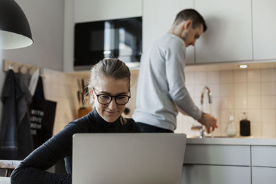 Woman in kitchen using laptop