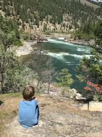 Rear view of boy sitting on rock