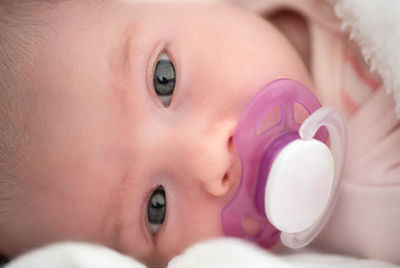 Close up of newborn baby lying on its side with white soother in mouth. newborn theme