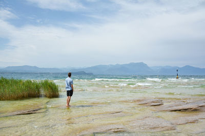 Man standing at beach against sky