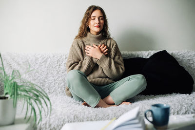 Young woman sitting on bed at home