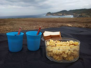 Close-up of food on table at beach against sky