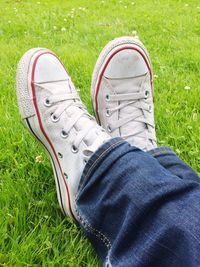 Low section of person with legs crossed at ankle on grassy field