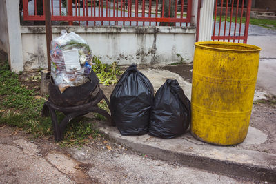 Garbage bin on street against wall in city