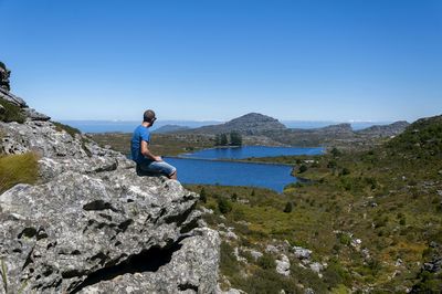 Rear view of man standing on rock against sky