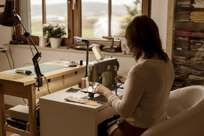 Caucasian brunette woman sewing fabric with a vintage, retro sewing machine. fashion, creation 