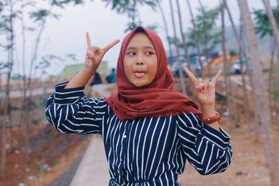 Young woman gesturing while standing outdoors