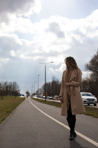 Woman standing on road against sky