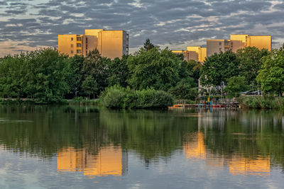 Scenic view of lake by trees and buildings against sky