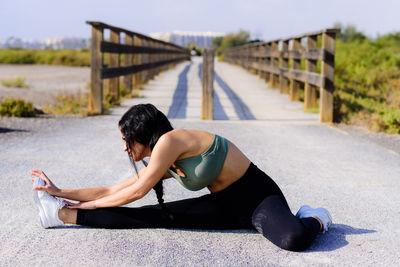 Woman stretching leg on road 