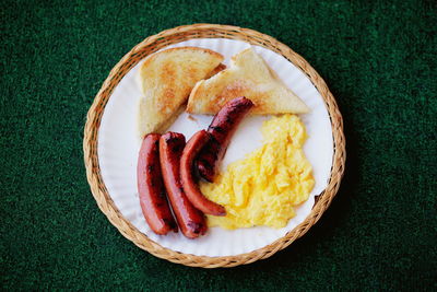 High angle view of fresh breakfast served in plate on green carpet