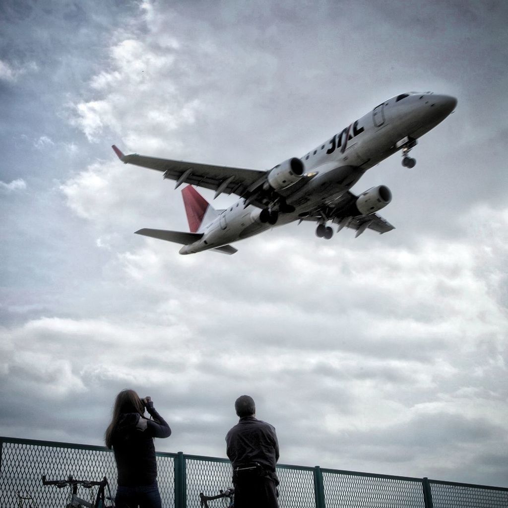 sky, cloud - sky, low angle view, flying, flag, lifestyles, patriotism, national flag, mid-air, leisure activity, cloudy, identity, men, cloud, wind, american flag, day, airplane