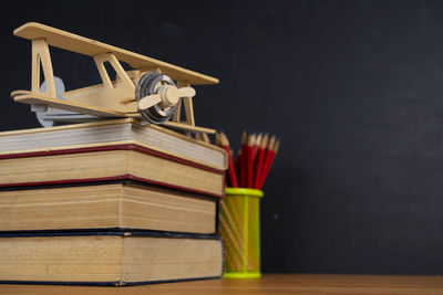 The books that are stacked and the pencil holders have a lot of red wooden pencils, plane model