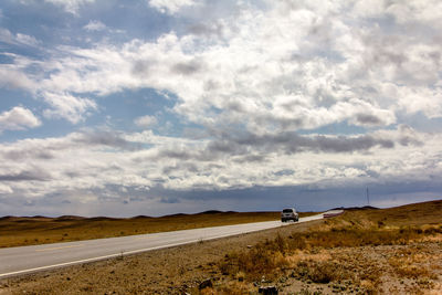 Road by rural landscape against sky