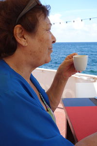 Side view of woman drinking coffee in boat