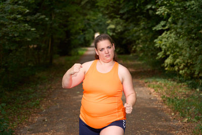 Portrait of young woman exercising on field