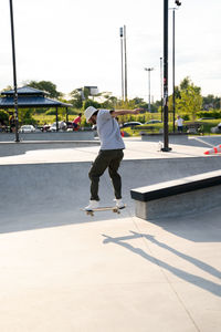 Rear view of man skateboarding on road