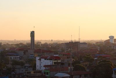 Buildings in city against clear sky during sunset