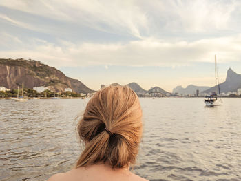 Rear view of woman looking at sea against cloudy sky