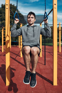 Young man doing pull-ups during his workout in a modern calisthenics street workout park