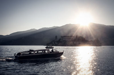 Boat sailing on river against sky during sunset