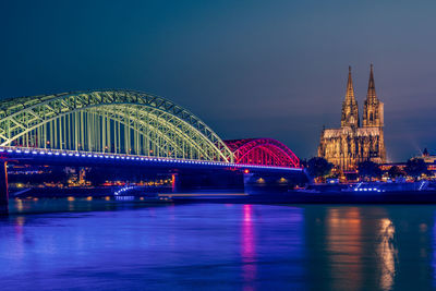 Illuminated bridge over river at night