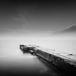 Pier amidst sea against cloudy sky during foggy weather