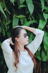 Young woman wearing hat standing by plants