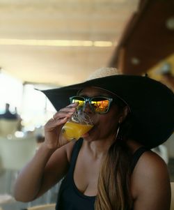 Woman wearing hat drinking juice at restaurant