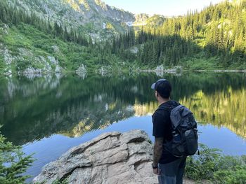 Rear view of man standing on rock by lake
