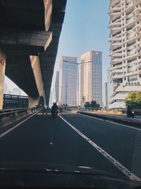 Road amidst buildings in city against sky