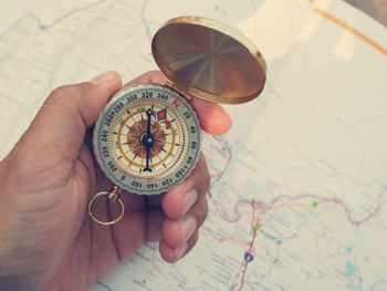 High angle view of person holding navigational compass over map