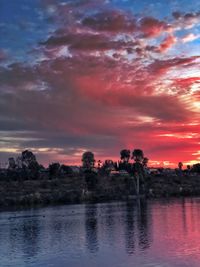 Scenic view of river and trees against sky at sunset