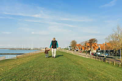 Grandfather with daughter on field against sky