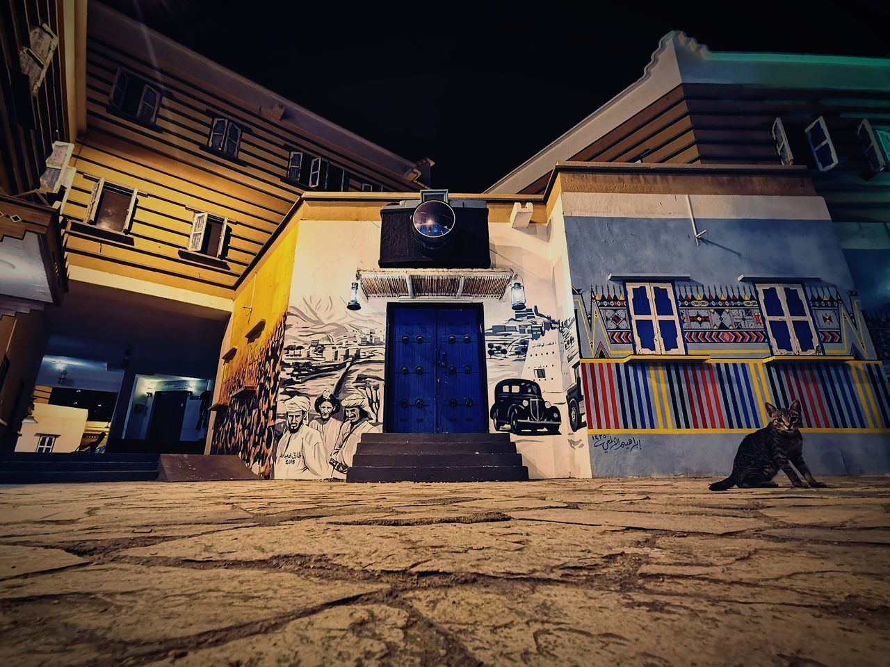 LOW ANGLE VIEW OF ILLUMINATED STREET AMIDST BUILDINGS