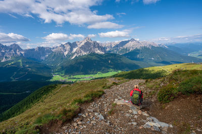 Rear view of woman sitting on mountain against sky