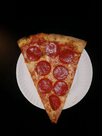 Close-up of pizza over black background