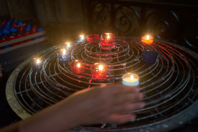 Cropped hand holding lit tea light candle