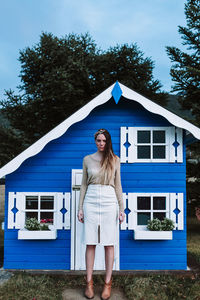 Woman standing by house against building