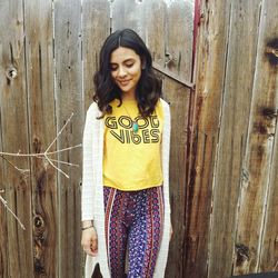 Portrait of smiling young woman standing against door