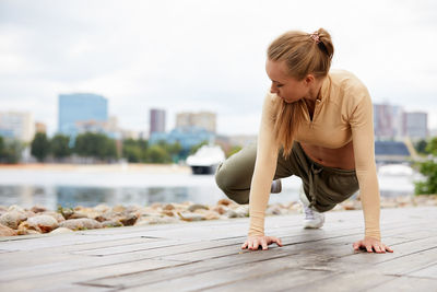 Side view of young woman exercising at beach