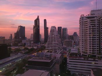 Modern buildings in city against sky during sunset