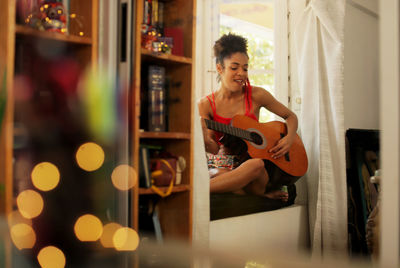 Young woman sitting on window