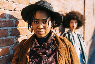 Portrait of young woman standing against wall