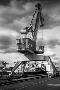 Low angle view of crane against cloudy sky