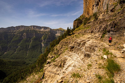 Rear view of man walking on mountain against sky