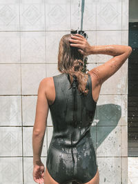 Rear view of woman taking bath in shower
