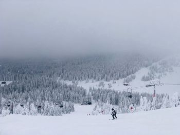 People skiing on snow covered land against sky