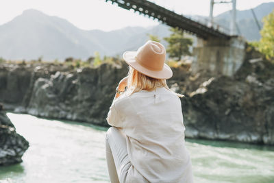 Midsection of woman wearing hat standing against water