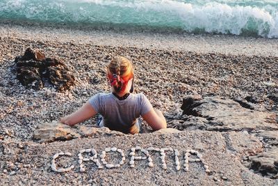 Woman sitting on rock at beach